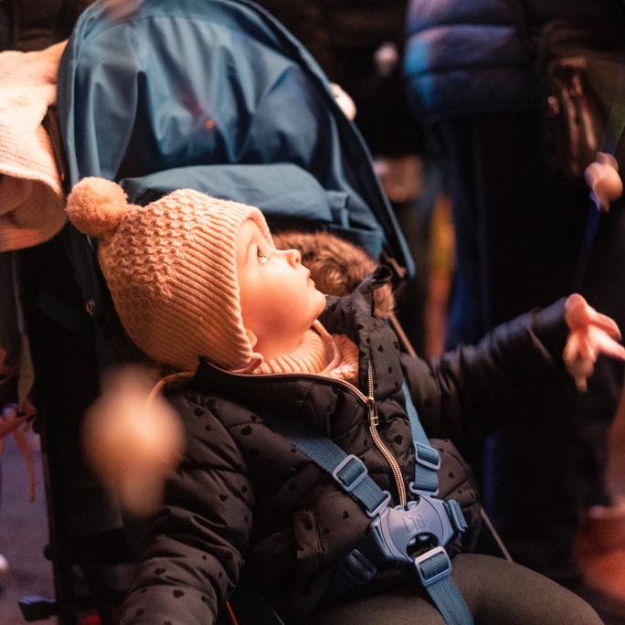 A young toddler in a pram watching a light show